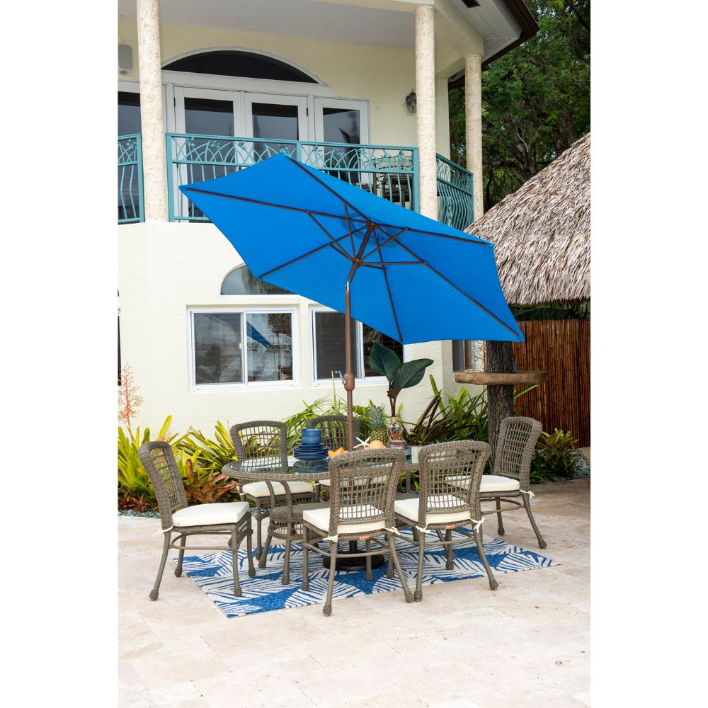Outdoor patio set with a blue umbrella on a patio with a white house in the background.