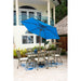Outdoor patio set with a blue umbrella on a patio with a white house in the background.