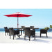 Outdoor dining set with red umbrella and chairs by a poolside.