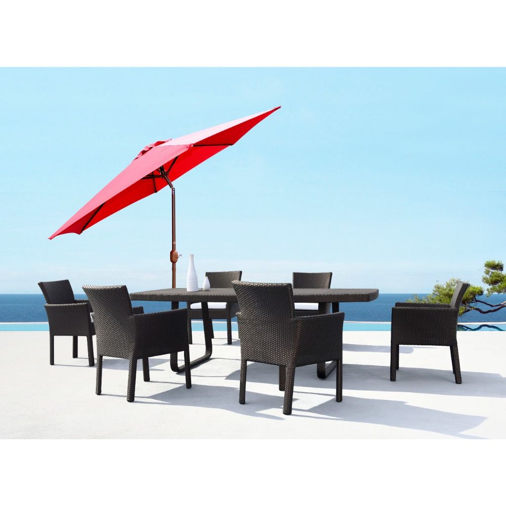 Outdoor dining set with a red umbrella and chairs by a pool with a blue sky background