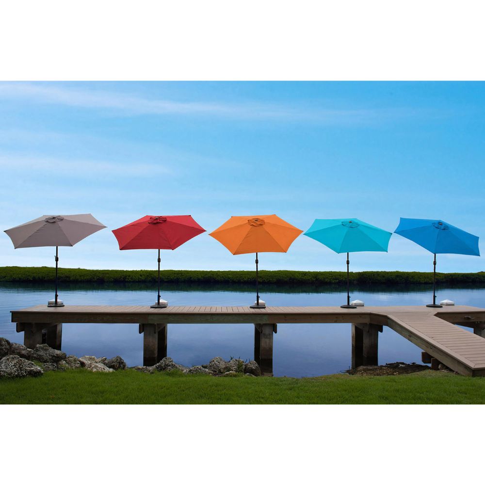 Five colorful patio umbrellas on a dock with a blue sky and water background.