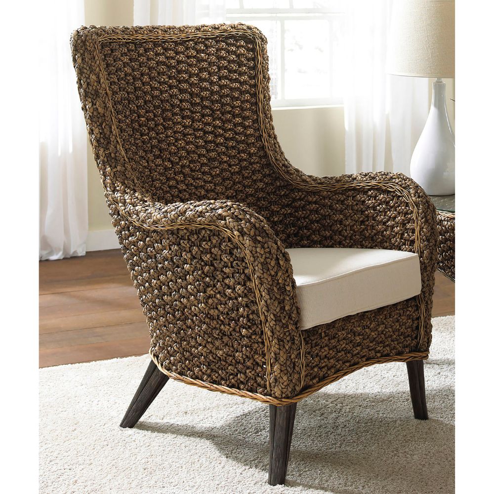 Woven armchair with a white cushion on a carpeted floor.