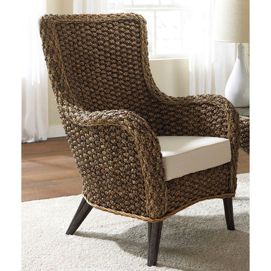 Woven armchair with a white cushion on a carpeted floor.