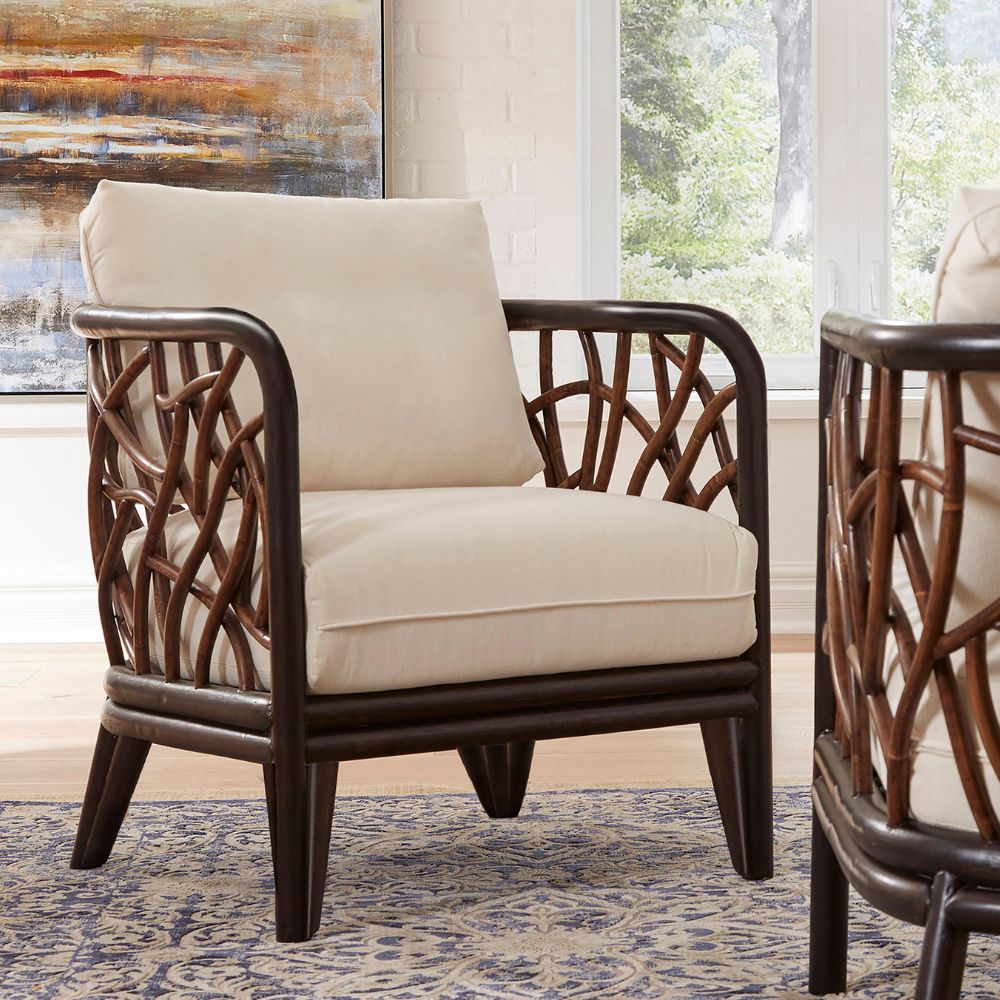 Beige armchair with wicker backrest in a room with large windows and abstract art.