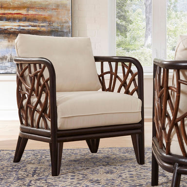 Beige armchair with wicker backrest in a room with large windows and abstract art.