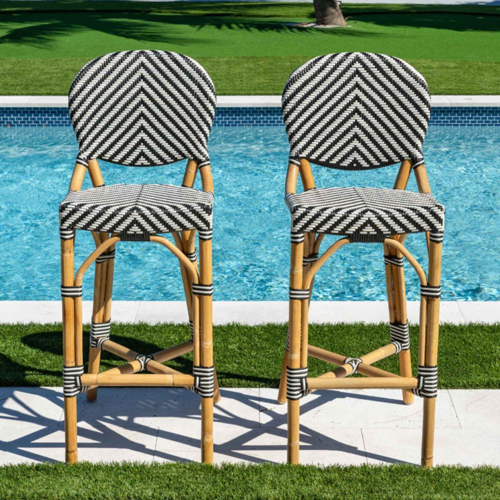 Two bar stools with striped backs and woven seats by a poolside.