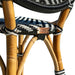 Close-up of a wicker chair with black, white, and blue striped pattern and visible brand logo.
