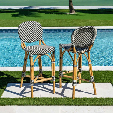 Two bar stools with striped cushions by a poolside.