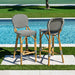 Two bar stools with striped cushions by a poolside.