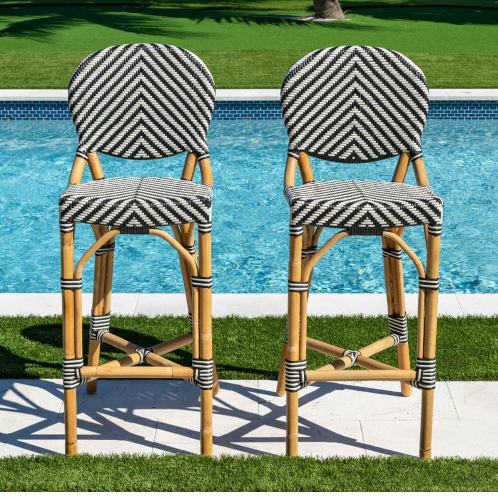 Two bar stools with black and white chevron patterned seats by a pool.