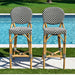 Two bar stools with black and white chevron patterned seats by a pool.