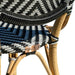 Close-up of a wicker chair with black, white, and blue patterned seat and wooden legs.