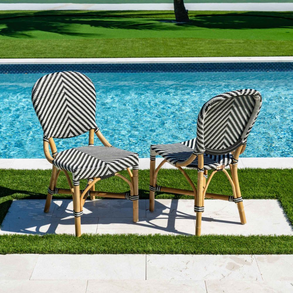 Two striped chairs and a table by a poolside on a sunny day.
