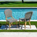Two striped chairs and a table by a poolside on a sunny day.