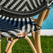 Close-up of a wicker chair with striped cushion and brand logo, blurred background