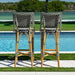 Two patterned bar stools by a poolside with greenery in the background