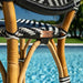 Close-up of a wicker chair with black and white striped cushion by a pool.