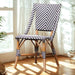 Wooden chair with black and white striped cushion in a bright room with curtains and plants.