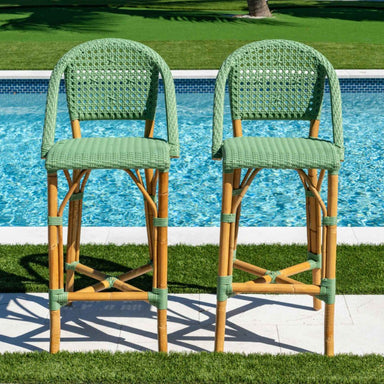 Two green wicker bar stools by a poolside