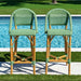 Two green wicker bar stools by a poolside