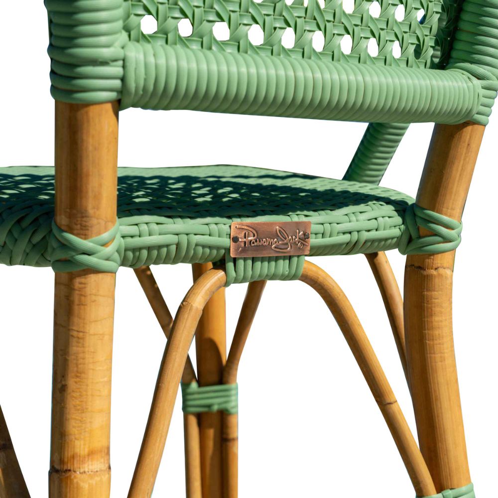 Close-up of a green wicker chair with a visible brand logo on a white background