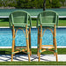 Two green and brown wicker bar stools by a poolside.