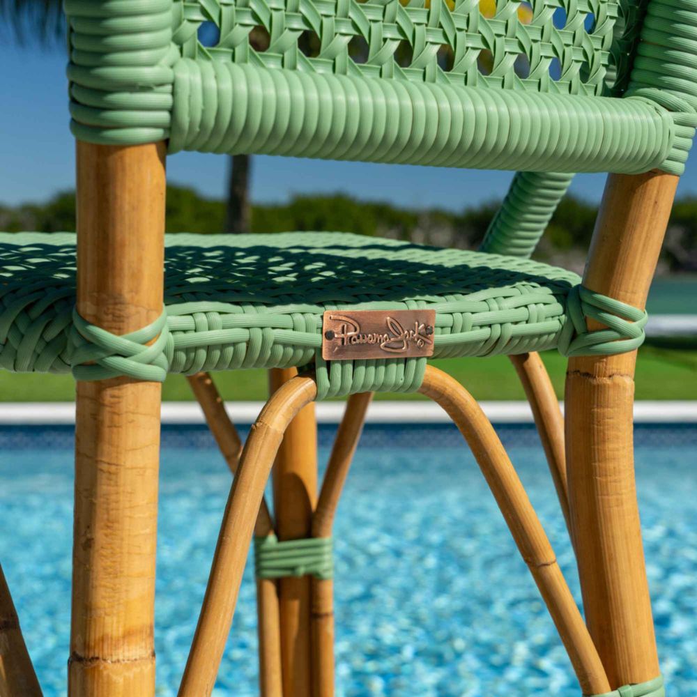 Green and brown wicker chair with a brand logo against a poolside background