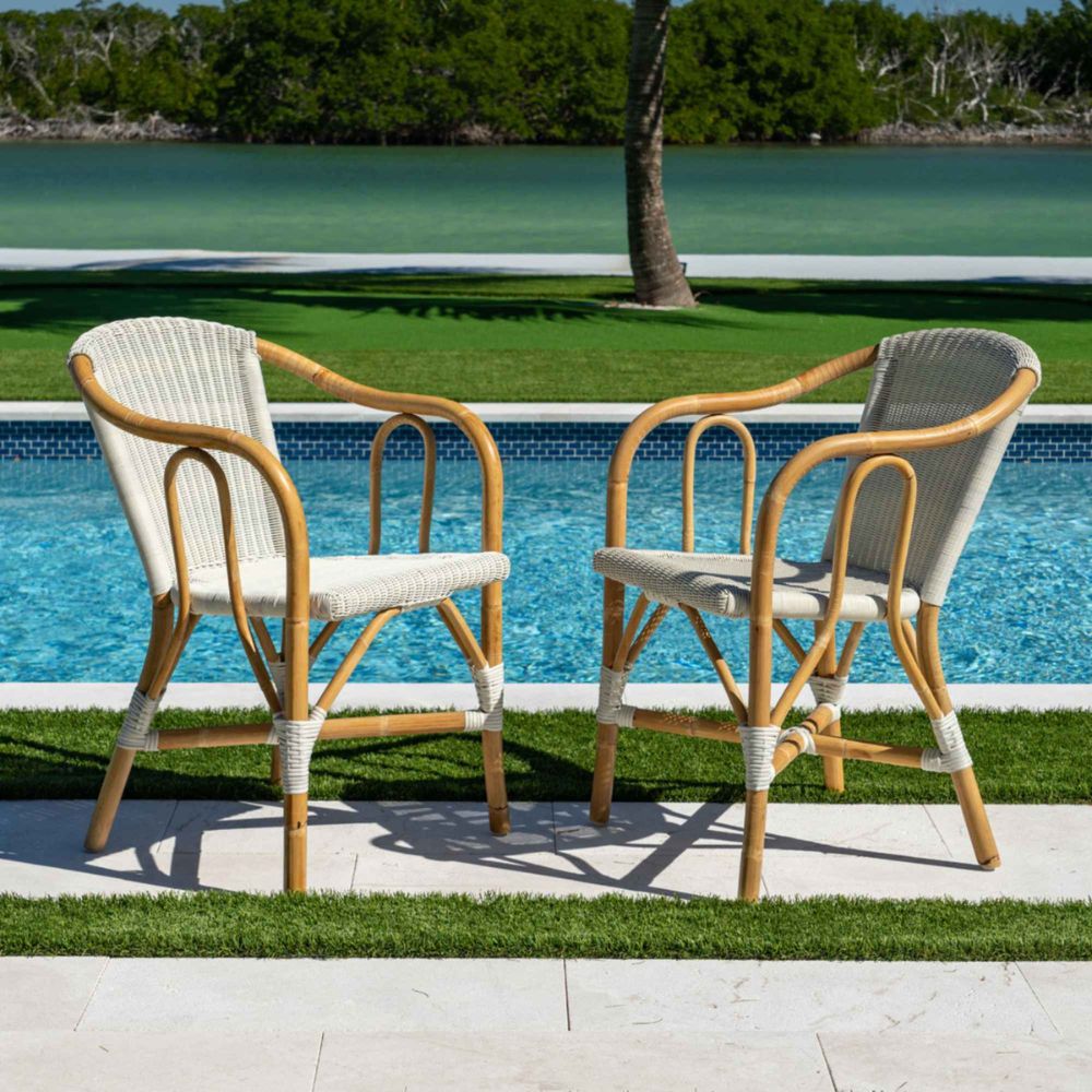Two wicker chairs by a pool with a scenic background