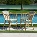 Two wicker chairs by a pool with a scenic background