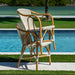 Two wicker chairs with white cushions by a poolside