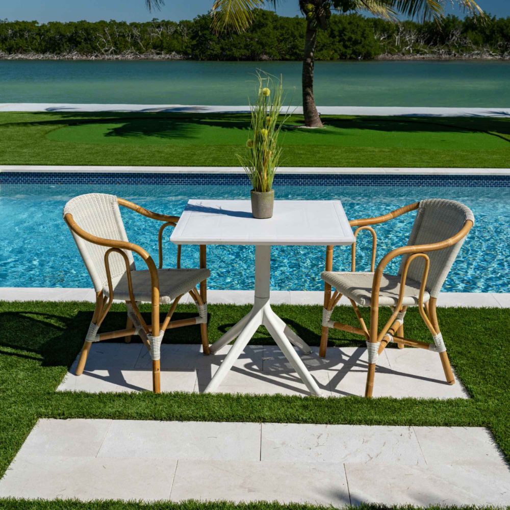 Outdoor dining table with chairs by a poolside