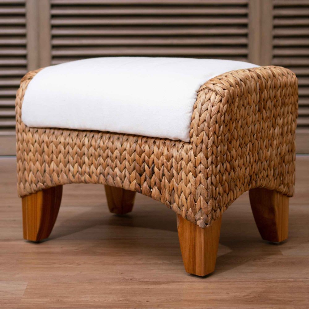 Woven stool with a white cushion on a wooden floor