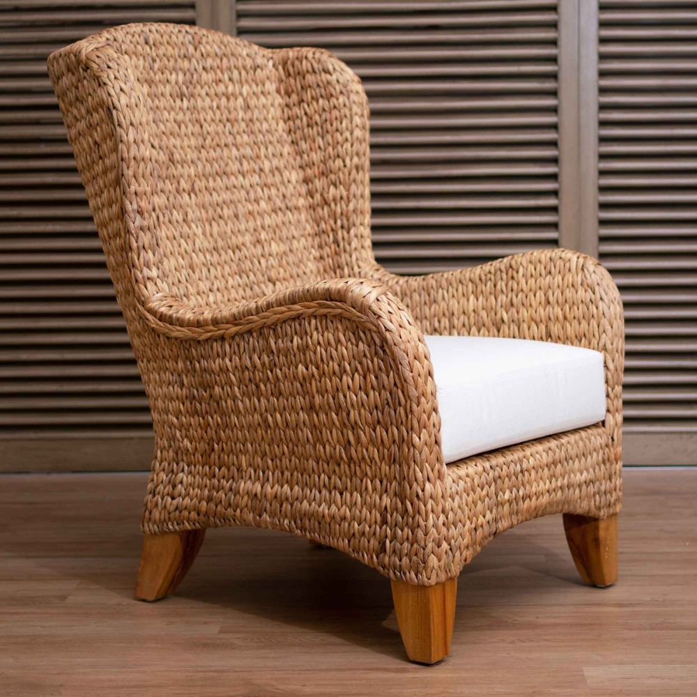 Woven armchair with a white cushion on a wooden floor.