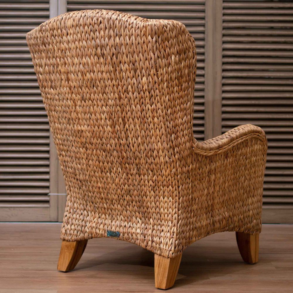 Woven armchair with wooden legs against a wooden panel background
