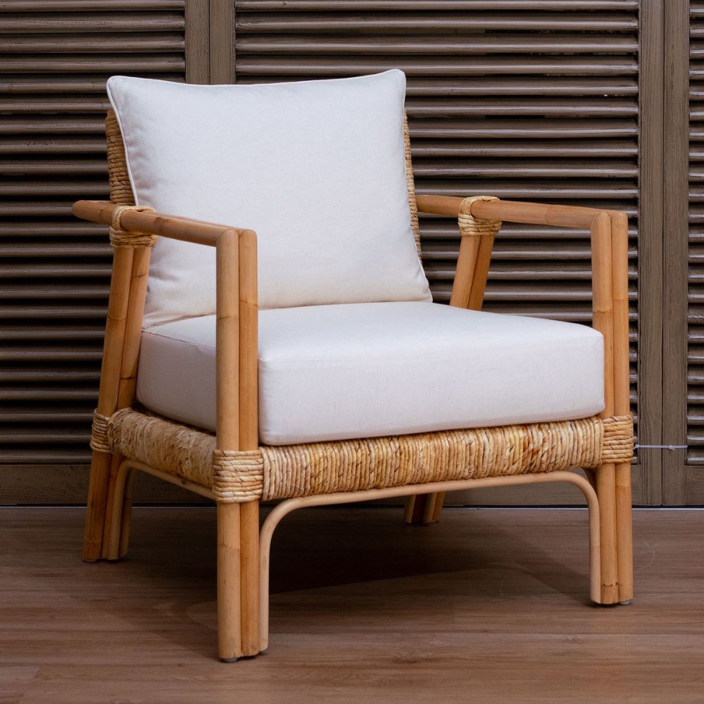 Wicker armchair with white cushion against a wooden slatted background