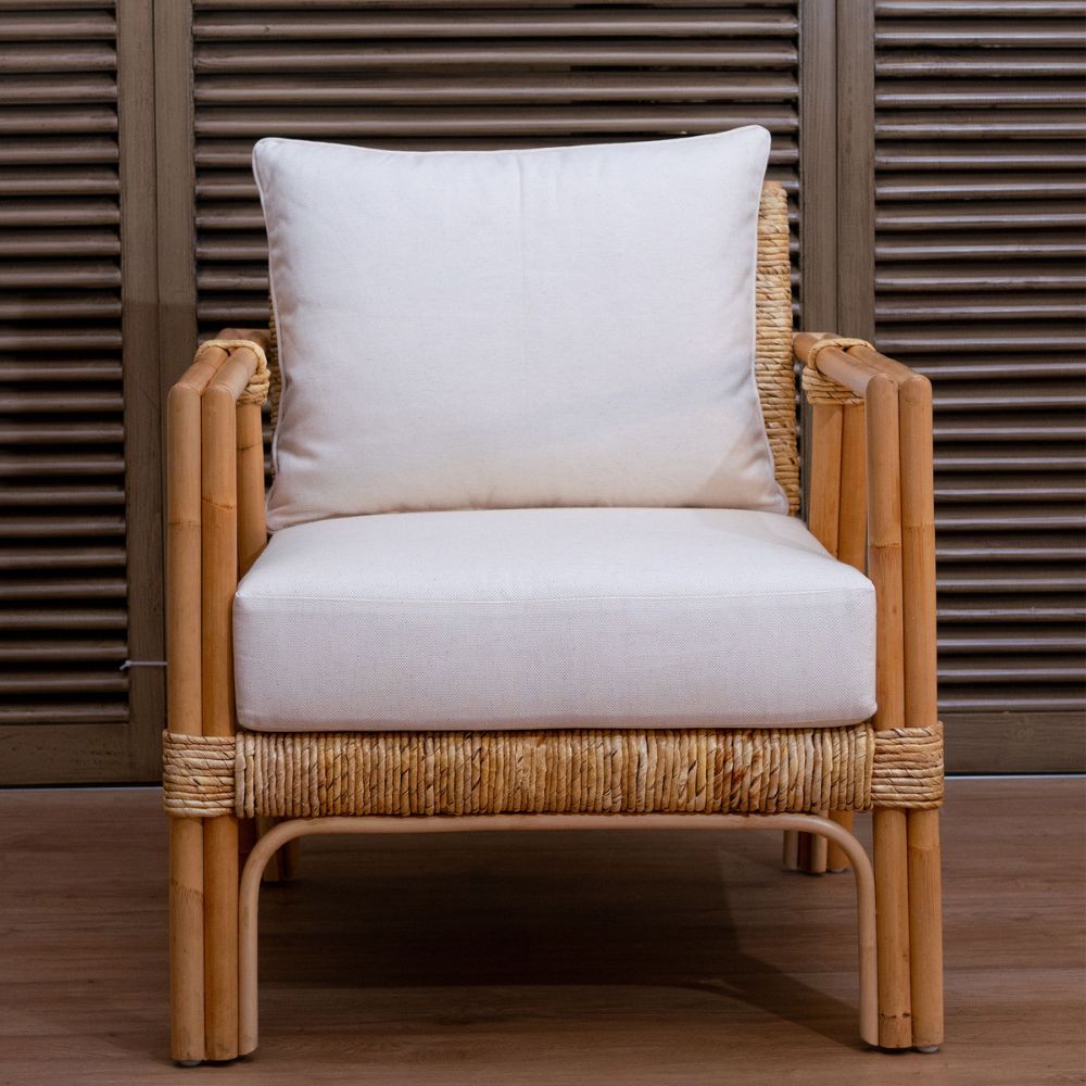 Rattan armchair with white cushion against a wooden background