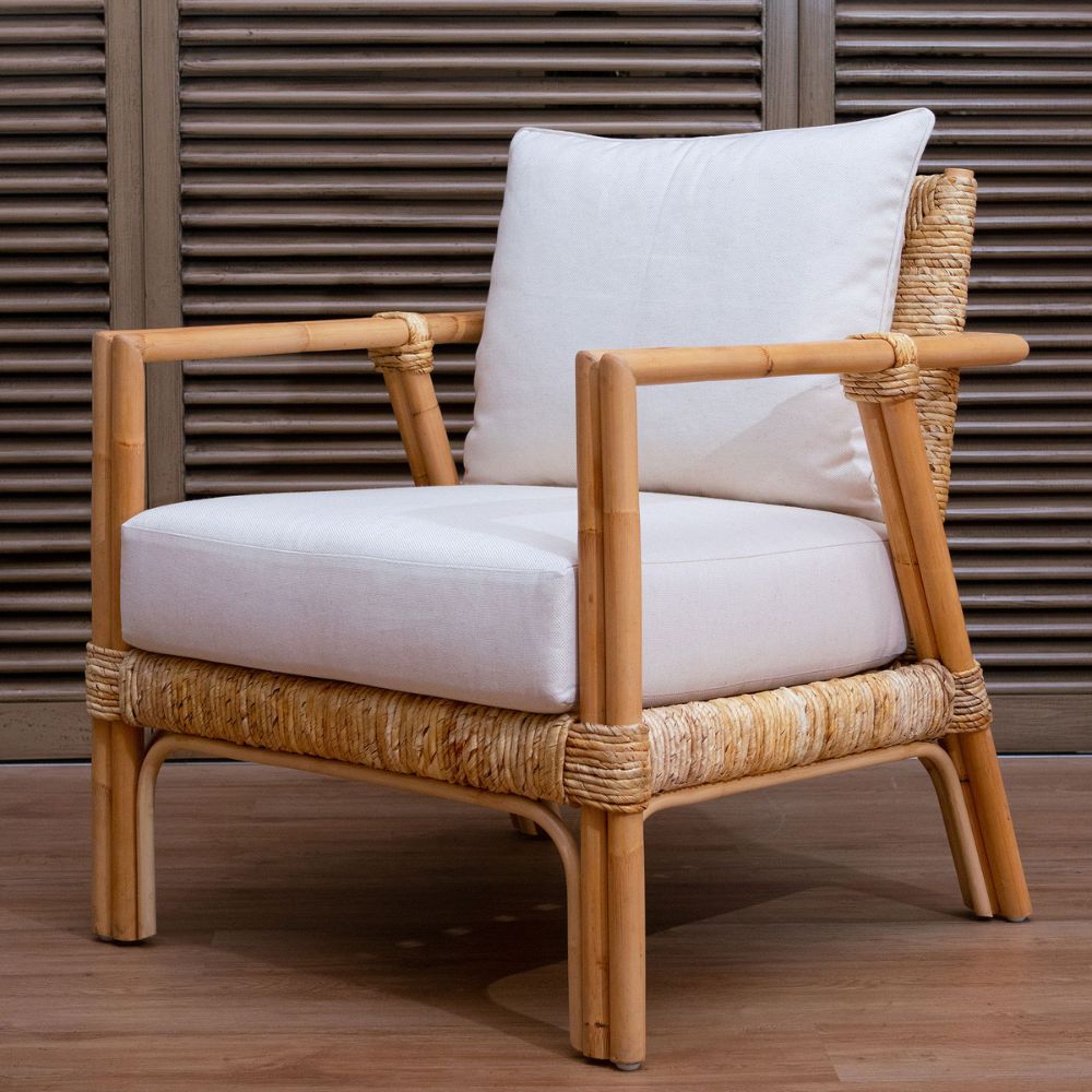 Rattan armchair with white cushions against a wooden background