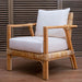 Rattan armchair with white cushions against a wooden background
