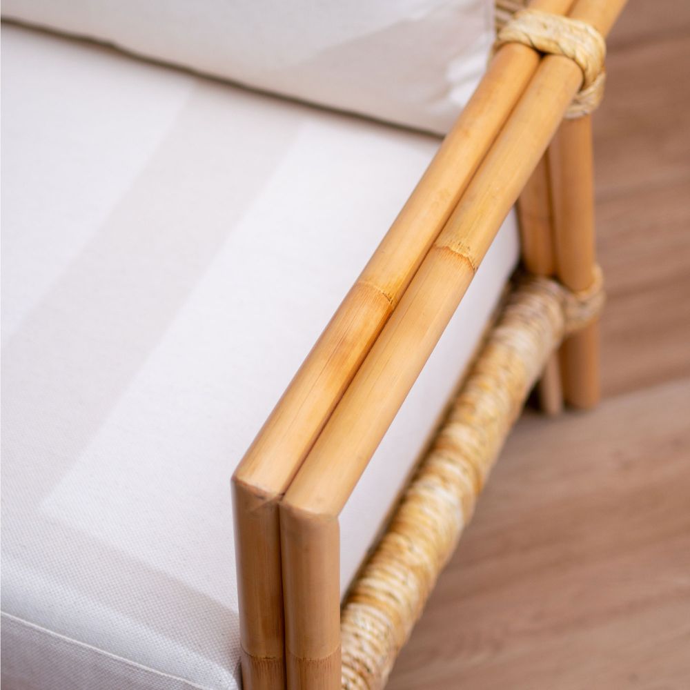 Close-up of a wicker chair with white cushion on a wooden floor.