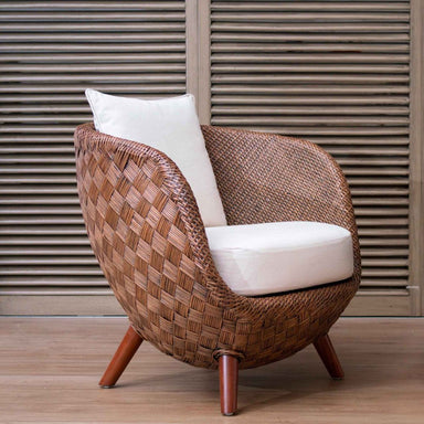 Woven chair with white cushion against a wooden slat background