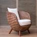 Woven chair with white cushion against a wooden slat background