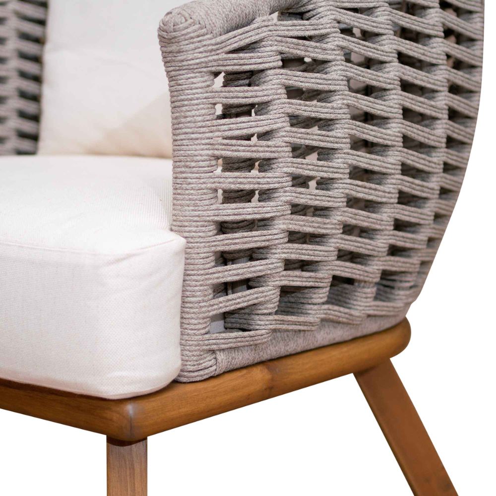 Wicker chair with wooden legs and white cushion on a neutral background