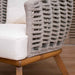 Wicker chair with wooden legs and white cushion on a blurred background