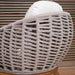 Close-up of a wicker chair with a white cushion against a wooden background