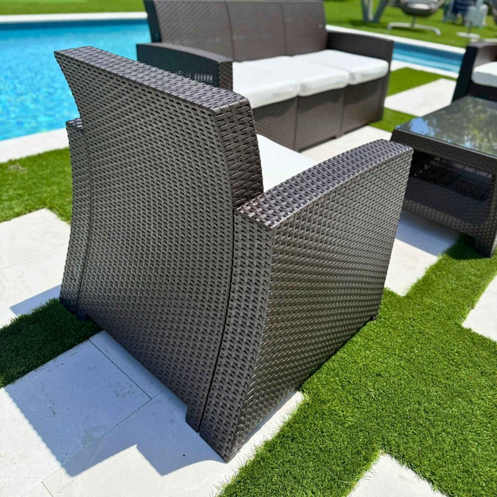 Brown wicker chair on a patio with a pool in the background