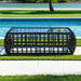 Black woven outdoor table by a poolside with green grass and water in the background