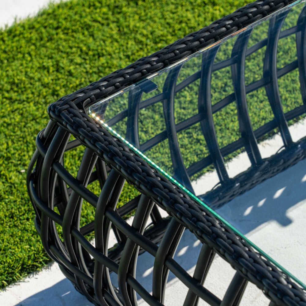 Black woven chair with glass top on a grassy background