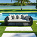 Outdoor sofa with cushions by a poolside with greenery