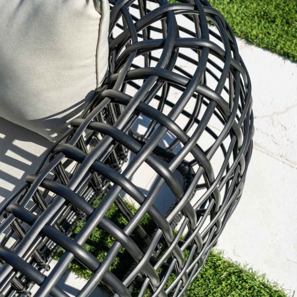 Close-up of a modern outdoor chair with woven design on a patio.