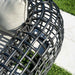 Close-up of a modern outdoor chair with woven design on a patio.